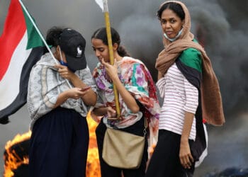 Sudanese women lift national flags by burning tyres as they take part in a demonstration on Sixty Street in the capital Khartoum, on May 23, 2020, to commemorate the first anniversary of a deadly crackdown carried out by security forces on Sudanese protesters during a sit-in outside army headquarters in the capital,  with a death toll of over a 100. (Photo by Ashraf SHAZLY / AFP) (Photo by ASHRAF SHAZLY/AFP via Getty Images)