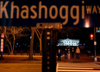People wait to cross the street near a protest sign reading "Khashoggi way" across the street from the White House in Washington, DC, on December 23, 2018. - Khashoggi, a Saudi contributor to the Washington Post, was killed on October 2 shortly after entering the kingdom's consulate in Istanbul in what Riyadh called a "rogue" operation. (Photo by ANDREW CABALLERO-REYNOLDS / AFP)        (Photo credit should read ANDREW CABALLERO-REYNOLDS/AFP via Getty Images)