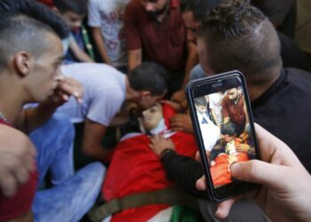 A relative of Palestinian Bara Hamamdah, who was shot dead during clashes with Israeli forces, uses a smartphone to take a picture during his funeral in the Dheisheh Refugee Camp, near the West Bank town of Bethlehem, on July 14, 2017. MUSA AL SHAER/AFP via Getty Images