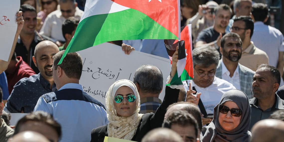 A woman raises a Jordanian national flag as she stands amidst public school teachers demonstrating and demanding pay raises, at the Professional Associations Complex in Jordan's capital Amman on October 3, 2019. (Photo by Khalil MAZRAAWI / AFP) (Photo by KHALIL MAZRAAWI/AFP via Getty Images)