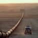 Saudi Arabia, main oil pipeline, car driving by at dusk. Northeastern Saudi Arabia near Iraqi border, 1985.