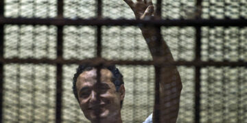 Egyptian political activist Ahmed Douma reacts as he stands behind dock bars during his trial in Cairo on June 3, 2013, on charges of insulting president Mohamed Morsi. Douma was convicted to serve six months in prison .  AFP PHOTO / KHALED DESOUKI        (Photo credit should read KHALED DESOUKI/AFP via Getty Images)
