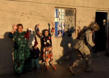 An Iraqi woman with her children raise their hands as US soldiers from the 4th Infantry division search their house in Tikrit, 180 Kilometers (110 miles) north of Baghdad, 19 December 2003. US soldiers captured Saddam hiding in a hole at a farm outside his hometown of Tikrit on December 13.         AFP PHOTO/JEWEL SAMAD / AFP PHOTO / JEWEL SAMAD        (Photo credit should read JEWEL SAMAD/AFP via Getty Images)