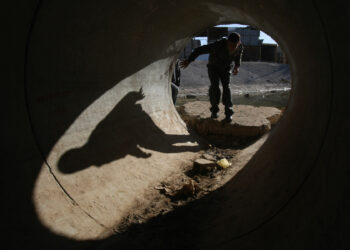 Palestinians walk through a sewage drain to pass under Israel's separation barrier November 27, 2007 at the West Bank village of Aram on the outskirts of Jerusalem. U.S. President George W. Bush is hosting Israeli, Palestinian and world leaders for a Middle East peace summit in Annapolis, Maryland later today.