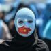 TOPSHOT - A demonstrator wearing a mask painted with the colours of the flag of East Turkestan and a hand bearing the colours of the Chinese flag attends a protest of supporters of the mostly Muslim Uighur minority and Turkish nationalists to denounce China's treatment of ethnic Uighur Muslims during a deadly riot in July 2009 in Urumqi, in front of the Chinese consulate in Istanbul, on July 5, 2018. - Nearly 200 people died during a series of violent riots that broke out on July 5, 2009 over several days in Urumqi, the capital city of the Xinjiang Uyghur Autonomous Region, in northwestern China, between Uyghurs and Han people. (Photo by OZAN KOSE / AFP) (Photo by OZAN KOSE/AFP via Getty Images)