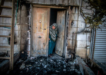 HUWARA, ISRAEL - 2023/02/28: A Palestinian woman looks outside her door that was torched by Jewish settlers in the occupied West Bank town of Huwara. US State Department spokesman Ned Price says the Biden administration expects Israel to prosecute those responsible for Sunday's deadly settler rampage of Huwara and provide compensation for the Palestinians whose homes and property were destroyed or damaged. (Photo by Eyal Warshavsky/SOPA Images/LightRocket via Getty Images)