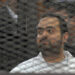 Egyptian prominent activicts Mohamed Adel stands in the accused dock during his trial on December 22, 2013, in Cairo. An Egyptian court sentenced three activists, Mohamed Adel, Ahmed Maher (unseen), the founder of the April 6 youth movement that led the revolt against former president Hosni Mubarak, and Ahmed Douma (unseen), all accused of spearheading the 2011 uprising against Mubarak to three years in jail for organising an unlicensed protest, judicial sources said. It was the first such verdict against non-Islamist protesters since the overthrow of president Mohamed Morsi in July, and was seen by rights groups as part of a widening crackdown on demonstrations by military-installed authorities. AFP PHOTO/STR        (Photo credit should read STRINGER/AFP via Getty Images)