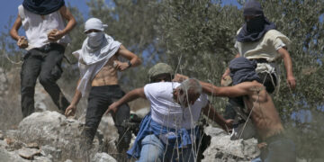 Masked Israeli settlers attack Palestinian olive farmers from the village of Hawara on fields near the settlement of Yitzhar in the Israeli-occupied West Bank, on October 7, 2020. (Photo by JAAFAR ASHTIYEH / AFP) (Photo by JAAFAR ASHTIYEH/AFP via Getty Images)