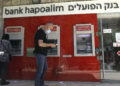 An Israeli man stands next to an automated teller machine of Bank Hapoalim in Jerusalem on May 1, 2020.  (Photo by MENAHEM KAHANA/AFP via Getty Images)