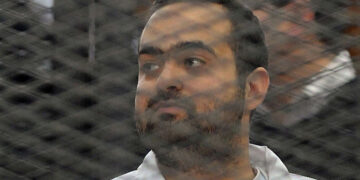 Egyptian prominent activicts Mohamed Adel stands in the accused dock during his trial on December 22, 2013, in Cairo. An Egyptian court sentenced three activists, Mohamed Adel, Ahmed Maher (unseen), the founder of the April 6 youth movement that led the revolt against former president Hosni Mubarak, and Ahmed Douma (unseen), all accused of spearheading the 2011 uprising against Mubarak to three years in jail for organising an unlicensed protest, judicial sources said. It was the first such verdict against non-Islamist protesters since the overthrow of president Mohamed Morsi in July, and was seen by rights groups as part of a widening crackdown on demonstrations by military-installed authorities. AFP PHOTO/STR