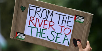 A Pro-Palestinian activist holds a placard reading 'From the River to the Sea' as they march through London, during a National Day of Action for Palestine on September 7, 2024. (Photo by JUSTIN TALLIS / AFP)