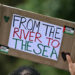 A Pro-Palestinian activist holds a placard reading 'From the River to the Sea' as they march through London, during a National Day of Action for Palestine on September 7, 2024. (Photo by JUSTIN TALLIS / AFP)