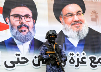 A member of security forces loyal to Yemen's Huthi group stands guard before a banner depicting Lebanese Hezbollah's slain leaders Hassan Nasrallah and Hashem Safieddine during an anti-Israel rally in solidarity with Gaza and Lebanon in the Huthi-controlled capital Sanaa on October 25, 2024. (Photo by Mohammed HUWAIS / AFP)