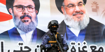 A member of security forces loyal to Yemen's Huthi group stands guard before a banner depicting Lebanese Hezbollah's slain leaders Hassan Nasrallah and Hashem Safieddine during an anti-Israel rally in solidarity with Gaza and Lebanon in the Huthi-controlled capital Sanaa on October 25, 2024. (Photo by Mohammed HUWAIS / AFP)