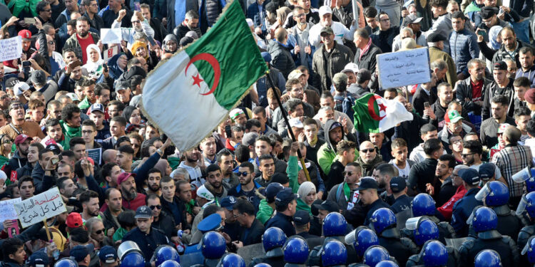 Algerian security surround protesters during an anti-government demonstration in the capital Algiers on December 11, 2019, ahead of the presidential vote scheduled for December 12. Algeria's contentious presidential election campaign is highlighting the vast gap between youth at the heart of a reformist protest movement and an ageing elite they see as clinging to power. The poll will see five candidates, all linked to ex-president Abdelaziz Bouteflika, compete for the top office. But protesters, whose mass mobilisation forced the ex-strongman to resign from his two-decade tenure in April, have rallied weekly to say sweeping reforms must come ahead of any vote. (Photo by RYAD KRAMDI / AFP)