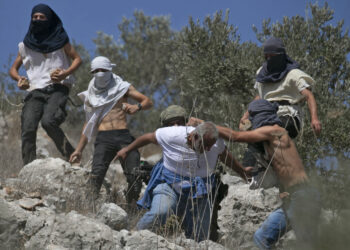 Masked Israeli settlers attack Palestinian olive farmers from the village of Hawara on fields near the settlement of Yitzhar in the Israeli-occupied West Bank, on October 7, 2020. (Photo by JAAFAR ASHTIYEH / AFP) (Photo by JAAFAR ASHTIYEH/AFP via Getty Images)